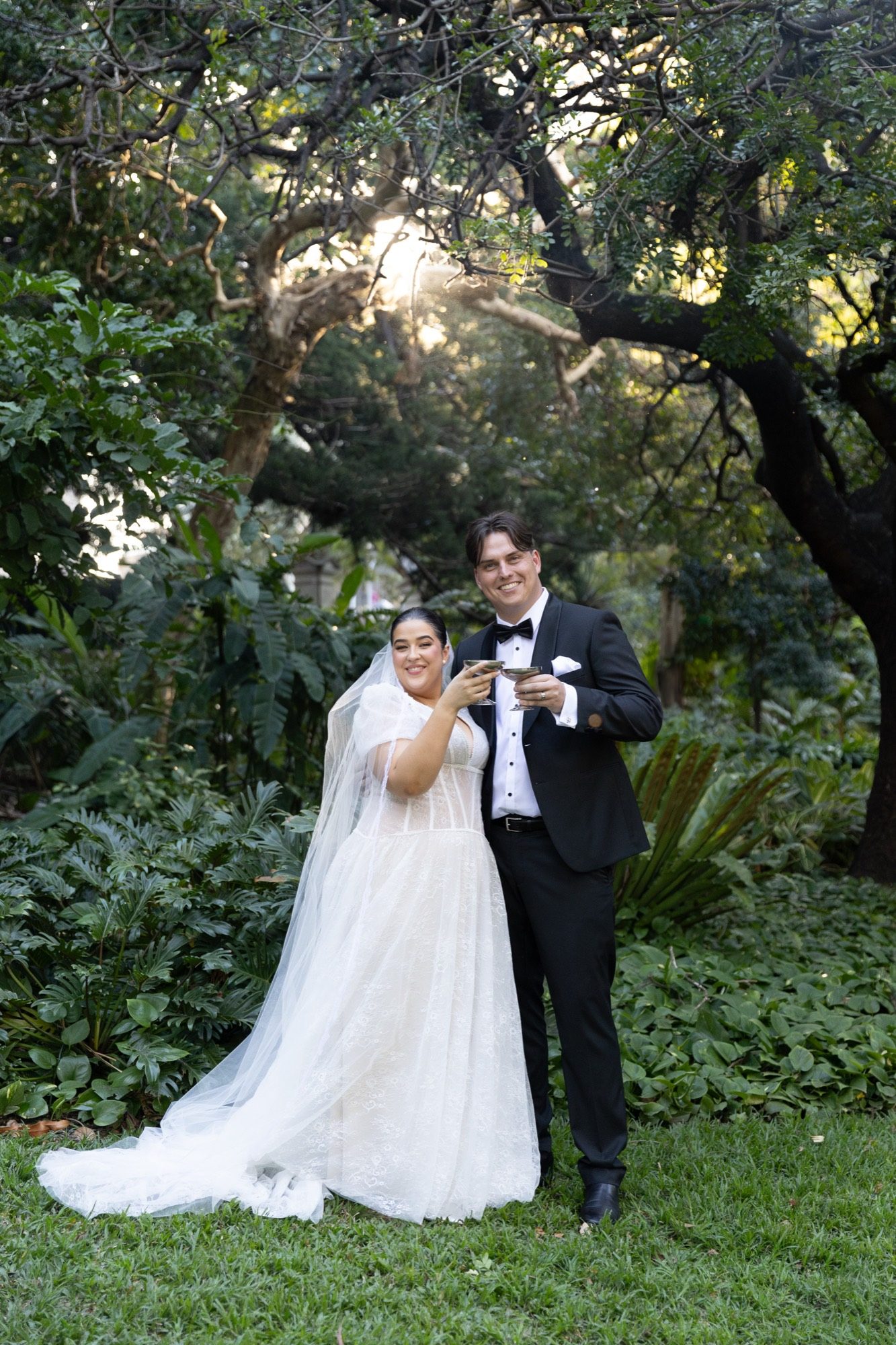 The bride and groom toasting with coupe glasses in a Brisbane garden