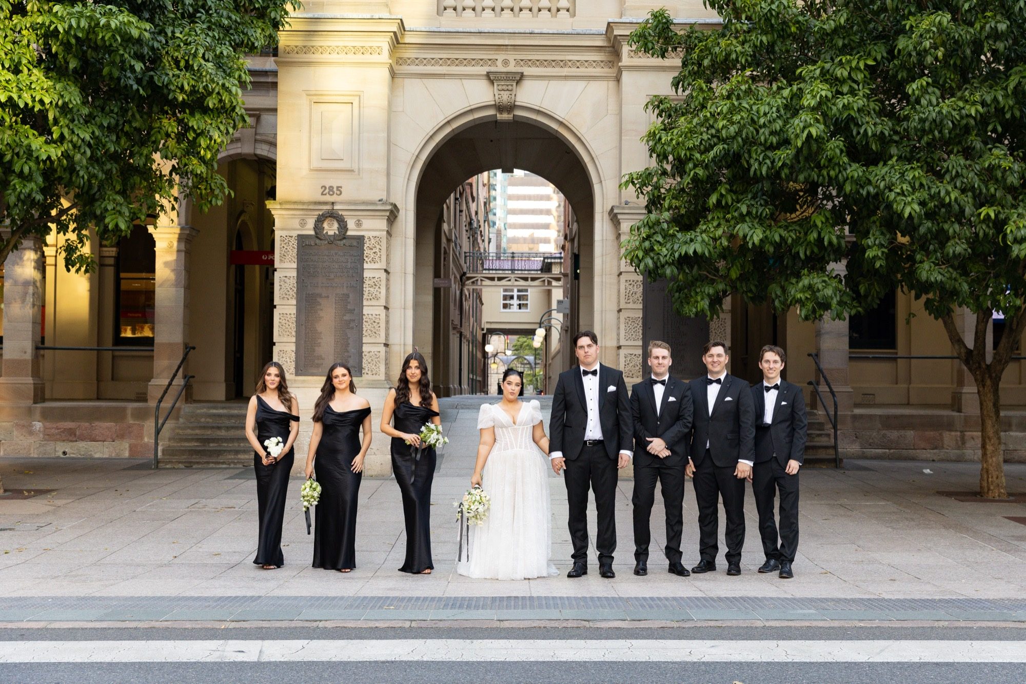 Amelia & Flynn — the bridal party beneath the sandstone arch on Queen Street, Brisbane