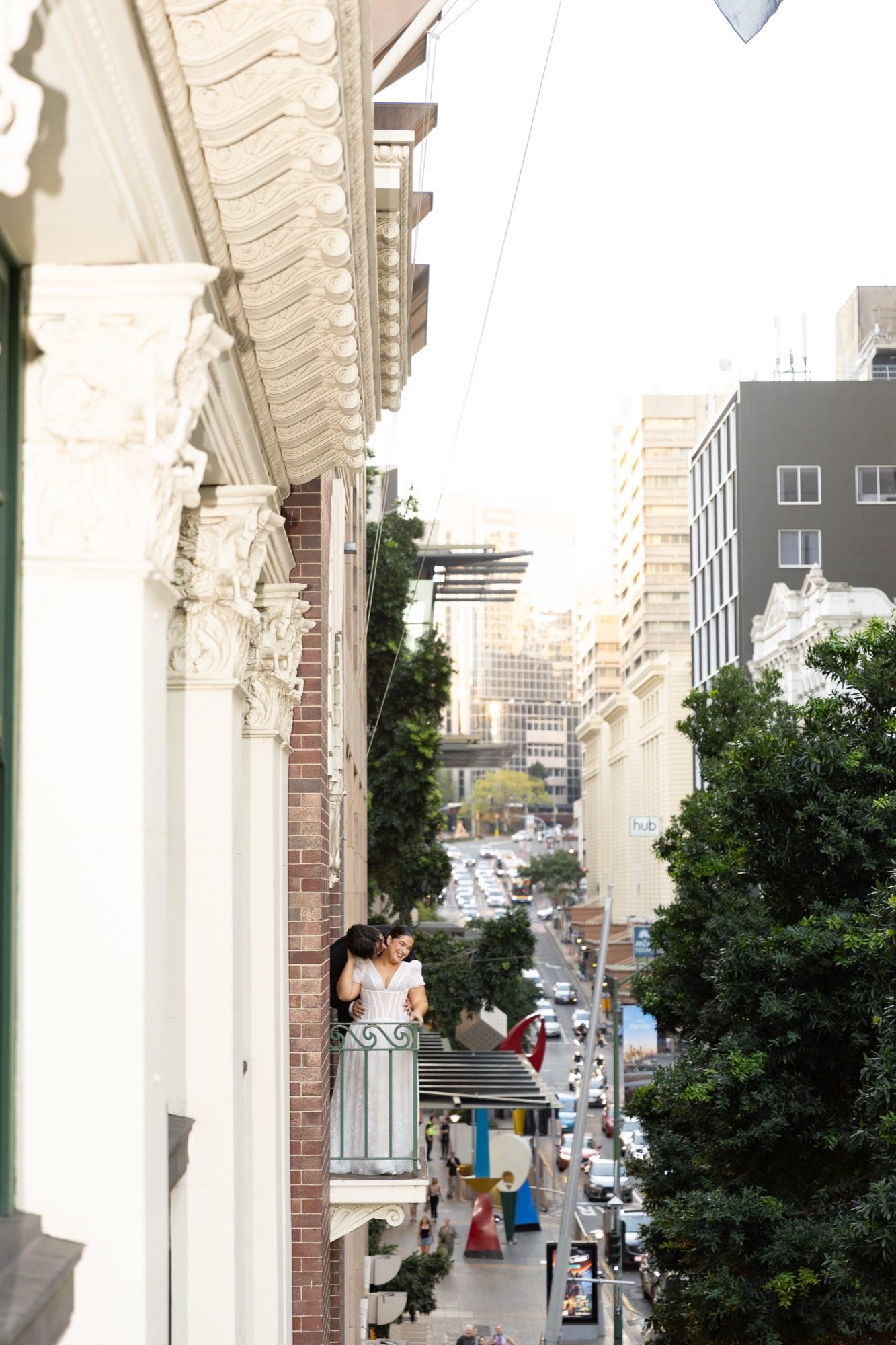 The couple embracing on a wrought-iron balcony above the city street, Brisbane